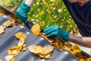 Man cleaning clogged gutters