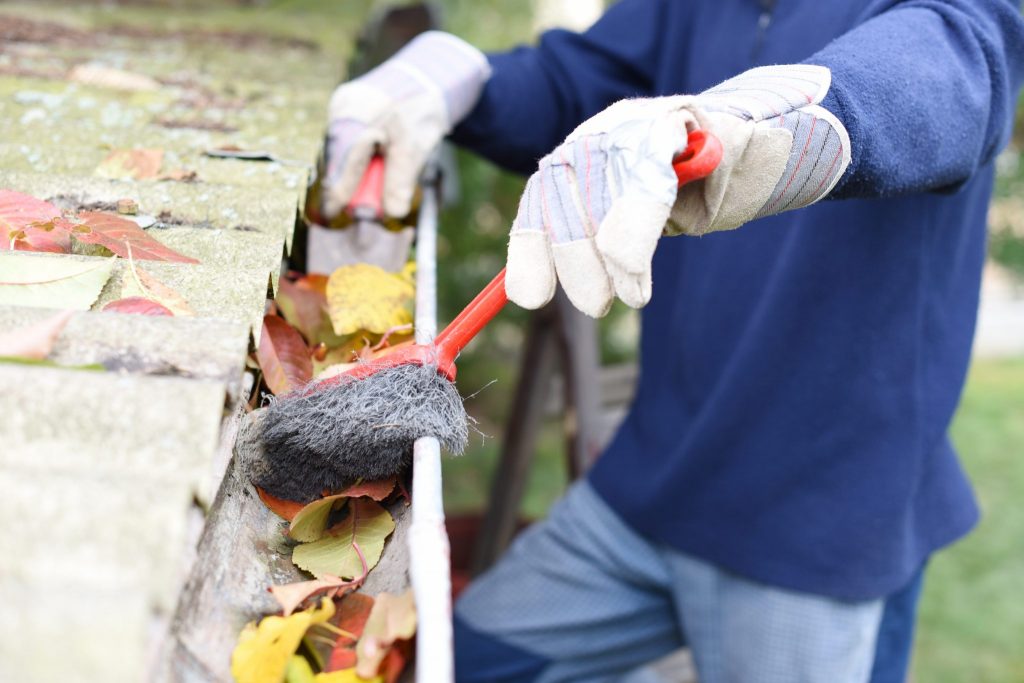 Man cleaning out a gutter with a brush