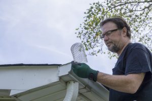 Man in gloves installing gutter guard